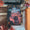 A book titled "The Executioners Three" by Susan Bennard is displayed on a wooden surface with autumn leaves, pinecones, a typewriter, and an orange box. The cover art features a dark fantasy illustration with two characters in a forest scene. image